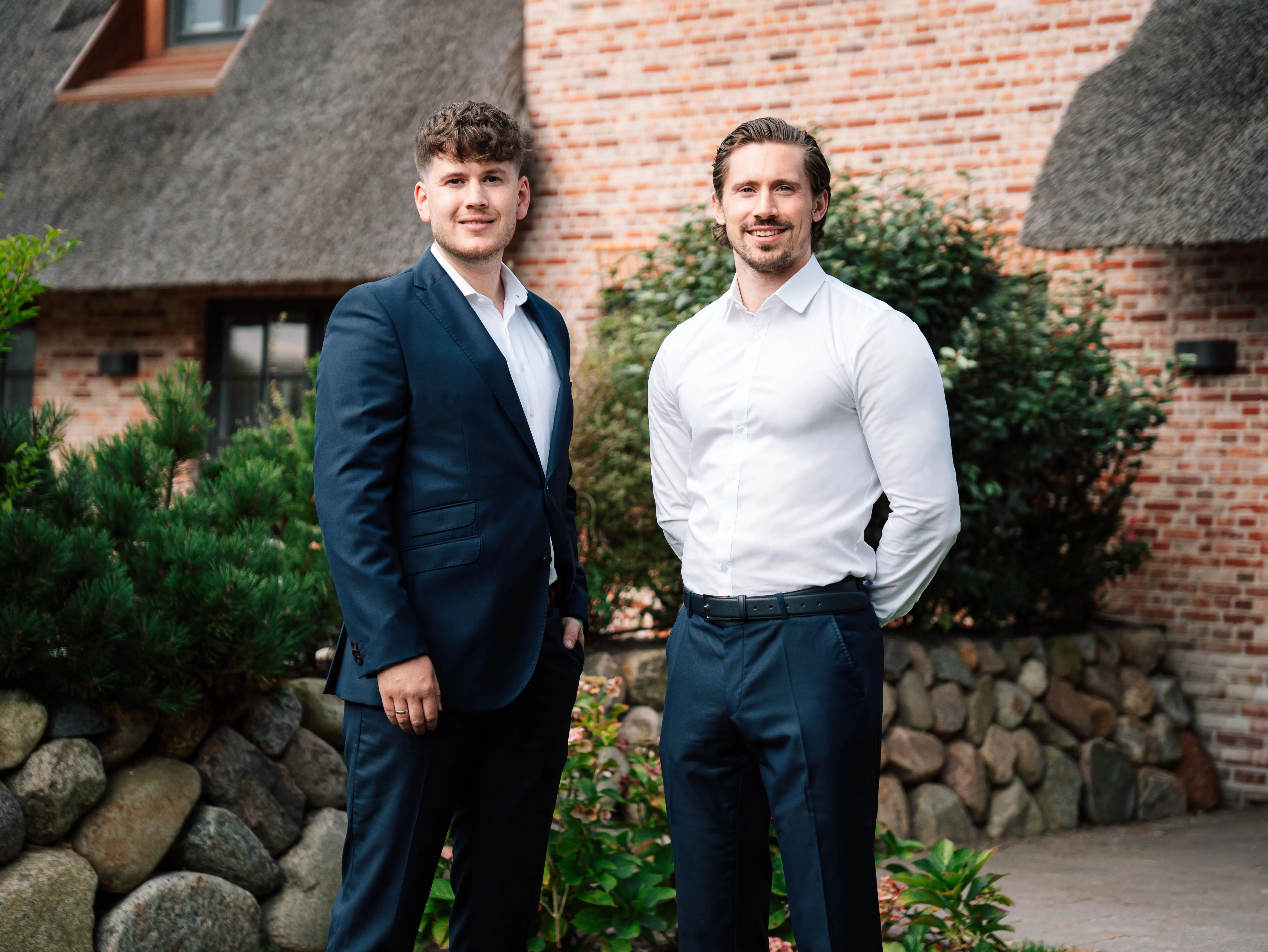 Lennart Dühnforth (links) und Moritz Gercke vor einem reetgedeckten Haus